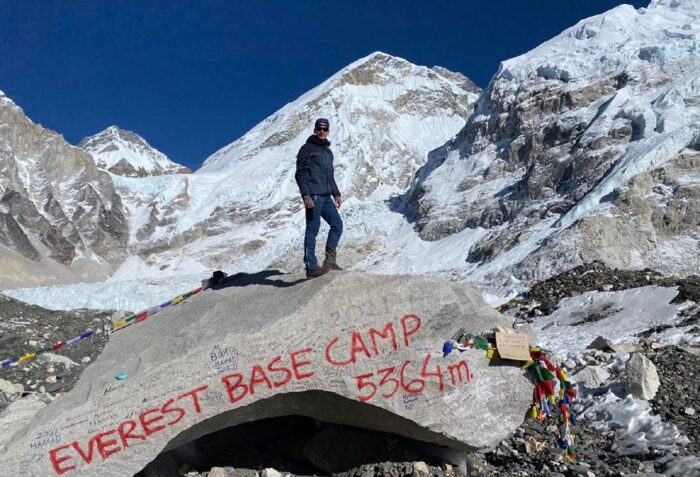 A trekker stands atop the famous Everest Base Camp stone. Photo: Alpine Ramble Treks

